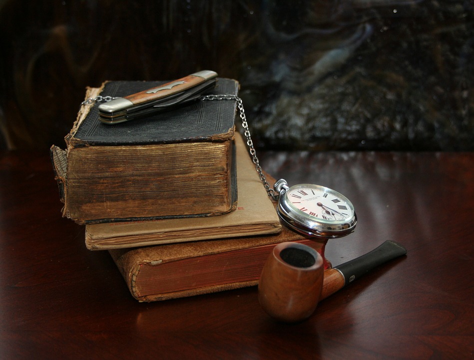 нож лежит на старых книгах, рядом трубка и часы