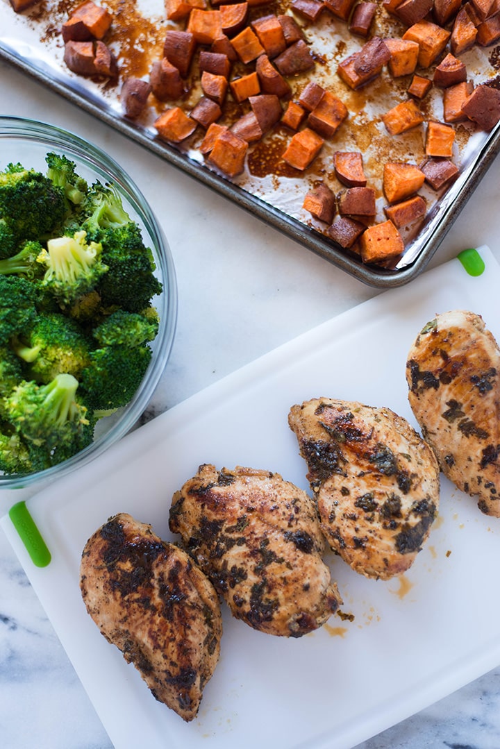 All the ingredients for how to meal prep the chicken, including the easy chicken breast recipe, sauteed broccoli, and roasted sweet potatoes, ready to be assembled.
