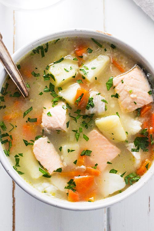 Overhead view of a bowl of Ukha, Russian fish soup. Fish is gently cooked with potatoes and carrots in a rich broth seasoned with bay and black pepper. 